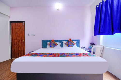 a bedroom with a large bed with blue curtains at FabExpress Sanva, Pallikaranai in Chennai