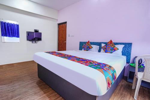 a bedroom with a large bed and a tv at FabExpress Sanva, Pallikaranai in Chennai