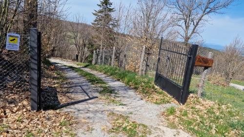 a gate on a dirt road next to a fence at - Agriturismo La Piaggia - forest view apartment on the ground floor 2 guests in Vivo dʼOrcia