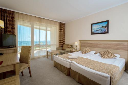 サニービーチにあるDIT Majestic Beach Resort - Ultra All Inclusiveのベッド、デスク、テレビが備わるホテルルームです。