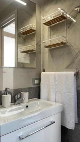 a white bathroom with a sink and a mirror at Bilocale Carrara Centro con giardino e parcheggio moto in Carrara
