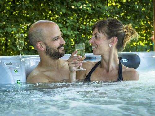 un hombre y una mujer en una bañera con una copa de vino en Guestroom Le Clerjus, 1 pièce, 2 personnes - FR-1-589-532, en Le Clerjus