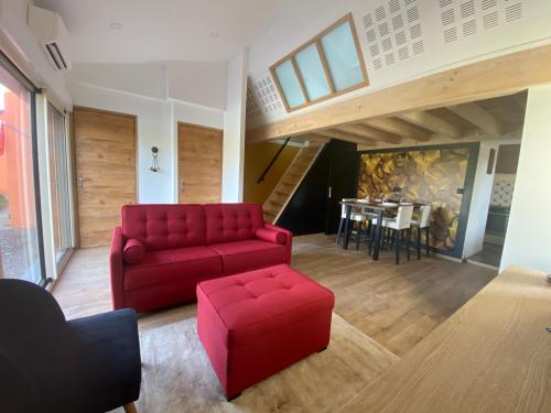 un salon avec un canapé rouge et une table dans l'établissement Le nid des coeuilles, à Carignan
