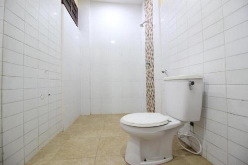 uma casa de banho com WC num quarto com azulejos brancos em RedDoorz @ Mantrijeron 2 em Yogyakarta