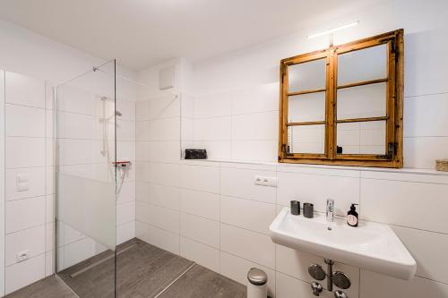 a bathroom with a sink and a glass shower at Fleischerei - Apartments, Cafe & Weinbar in Hinterstoder