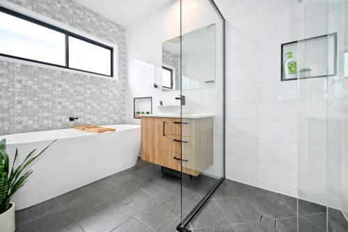 a bathroom with a tub and a sink at Stylish, Beachside 4 b/r Dream Home - 8 guests ZD7 in Kawana Waters
