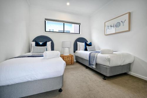 a bedroom with two beds and a chair at Stylish, Beachside 4 b/r Dream Home - 8 guests ZD7 in Kawana Waters
