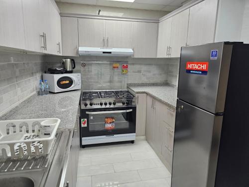 a kitchen with a stainless steel refrigerator and a stove at Modern & Cozy 1 Bedroom and 1 Living Room Apartment near Sharjah University in Sharjah