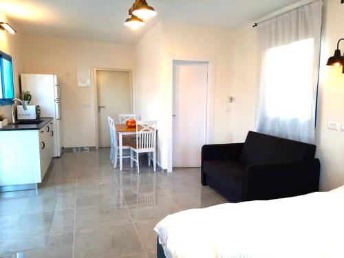 a living room with a black couch and a table at Bein Tavor Lekineret- quiet cabin in Sde Ilan in Sede Ilan