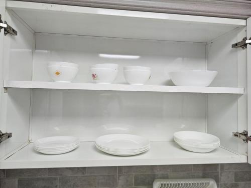 a shelf with white bowls and plates on it at Modern & Cozy 1 Bedroom and 1 Living Room Apartment near Sharjah University in Sharjah