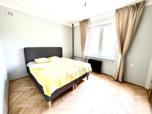 - une chambre avec un lit doté de draps jaunes et une fenêtre dans l'établissement Cosy, Comfy, Polin, Old Town, à Varsovie