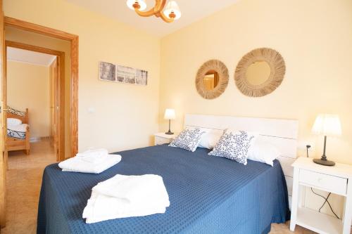 a bedroom with a blue bed with towels on it at Global Properties, Apartamento con piscina y terraza en Canet playa in Canet de Berenguer