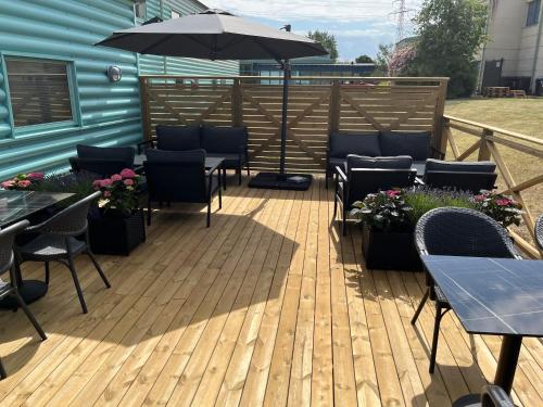 a deck with tables and chairs and an umbrella at Good Morning Lund in Lund