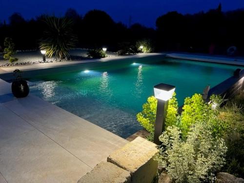 a large swimming pool at night with lights in it at Le nid des coeuilles in Carignan