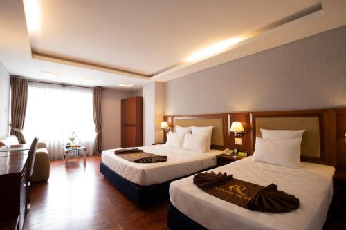 a hotel room with two beds and a window at Aristo Saigon Hotel in Ho Chi Minh City