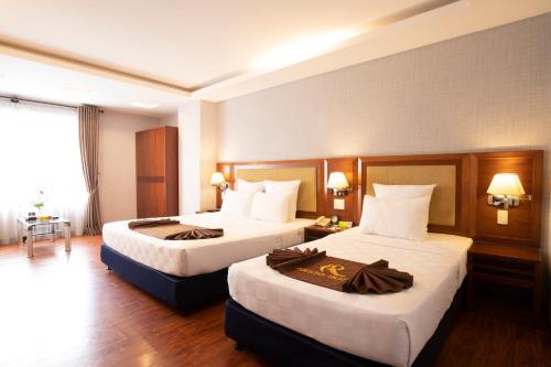 a hotel room with two beds and a window at Aristo Saigon Hotel in Ho Chi Minh City