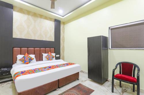 - une chambre avec un grand lit et une chaise rouge dans l'établissement FabExpress GS Residency, à Varanasi