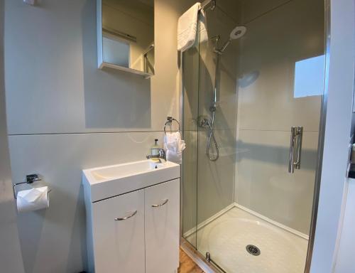 baño blanco con ducha y lavamanos en Stunted Totara, Unit 4, en Twizel