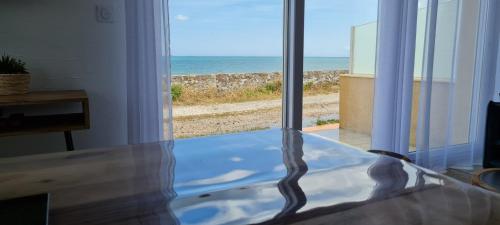 a glass table with a view of the ocean at Relais des îles Saint Marcouf in Saint-Marcouf