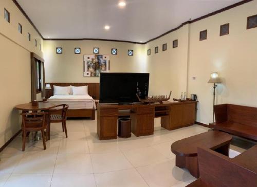 a bedroom with a bed and a desk with a television at Hotel & Villa Bukit Indah Saumlaki by LeGreen 