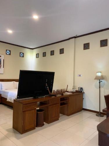 a bedroom with a bed and a flat screen tv at Hotel & Villa Bukit Indah Saumlaki by LeGreen in Saumlaki