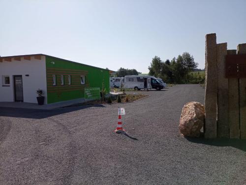 a parking lot with a green building and a traffic cone at Fichtelpark in Kirchenlamitz