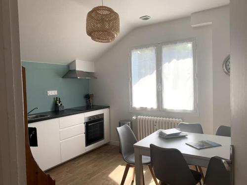 une cuisine et une salle à manger avec une table et des chaises dans l'établissement Le Nid des Fées appartement T3 rénové accès jardin, à La Bourboule