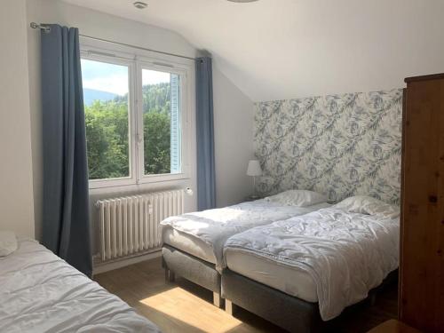 une chambre avec deux lits et une fenêtre dans l'établissement Le Nid des Fées appartement T3 rénové accès jardin, à La Bourboule