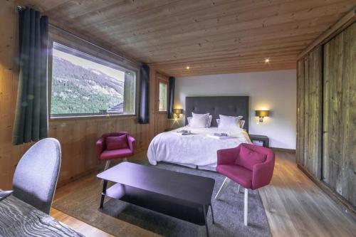 1 dormitorio con 1 cama, 2 sillas y una ventana grande en Chalet Kalliste spacieux Meribel 5 min des pistes avec Spa en Les Allues