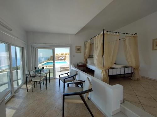 ein Schlafzimmer mit einem Bett und Stühlen sowie einem Pool in der Unterkunft Apollon Village Hotel in Anafi