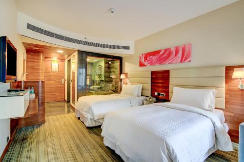a hotel room with two beds and a bathroom at Four Points By Sheraton Visakhapatnam in Visakhapatnam
