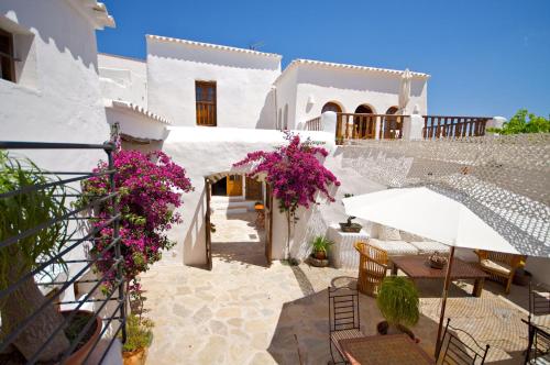 a patio with tables and chairs and pink flowers at Agroturismo Can Pardal in Sant Miquel de Balansat