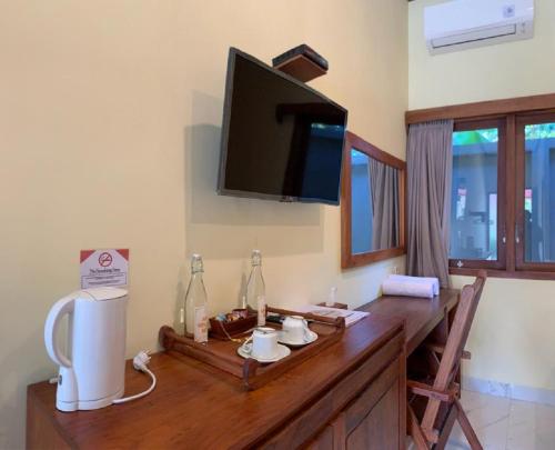 a room with a wooden table with a television on the wall at Hotel & Villa Bukit Indah Saumlaki by LeGreen in Saumlaki