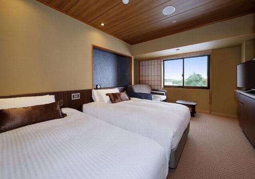 a hotel room with two beds and a flat screen tv at Hakodate Hotel Banso in Hakodate