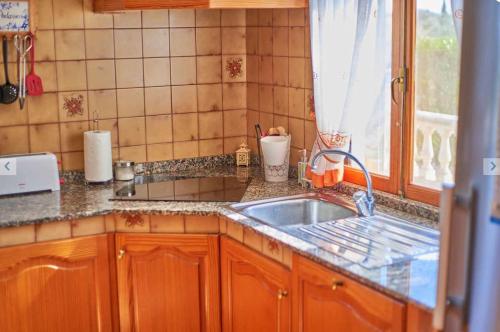 um balcão de cozinha com um lavatório e uma janela em Finca Can Bagur Ventolra em Biniali