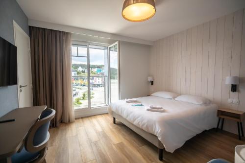 クロゾンにあるHôtel de la Baieのベッドと大きな窓が備わるホテルルームです。