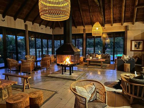 a large room with a fireplace and tables and chairs at Barefoot Addo Elephant Lodge in Addo