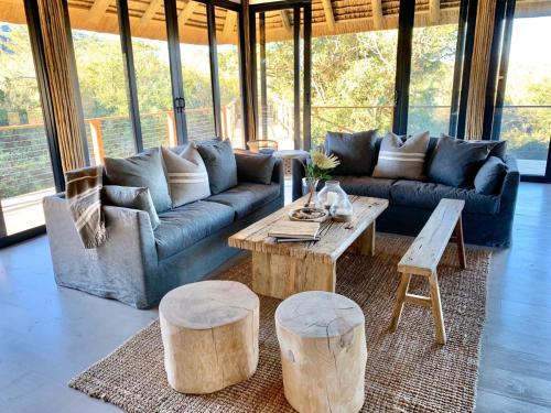 a living room with a couch and a table and stools at Barefoot Addo Elephant Lodge in Addo
