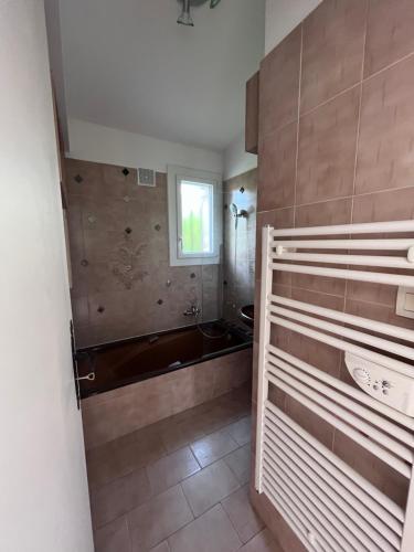 une salle de bain avec une baignoire et une fenêtre dans l'établissement Appartement avec piscine privée 4 à 6p 5min de la plage, à La Garonnette-Plage