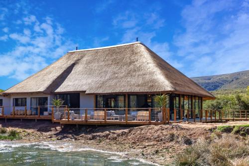 una casa con techo de paja en una playa en Barefoot Addo Elephant Lodge, en Addo