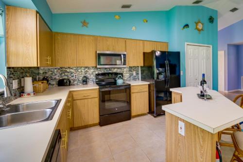 a kitchen with a sink and a refrigerator at Pet-Friendly Sebastian Home with Porch and Lake View! in Sebastian