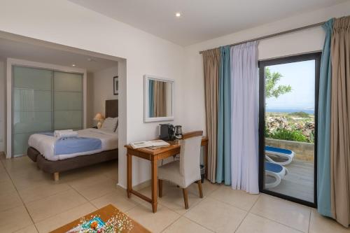 a hotel room with a bed and a desk and a window at Hotel Ta' Cenc & Spa in Sannat