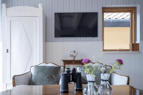 a dining room with a table and a television on the wall at Stammershalle Badehotel in Bådsted