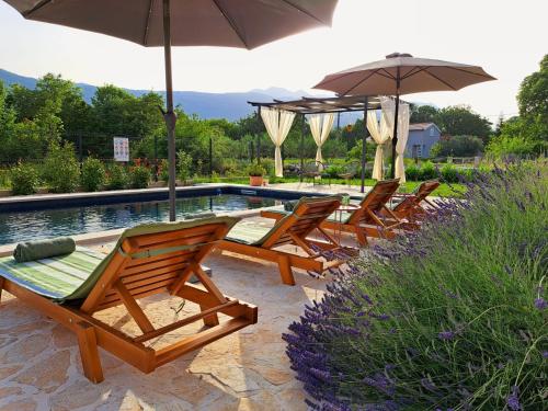 a group of chairs and umbrellas next to a pool at Villa Vinka in Kozica