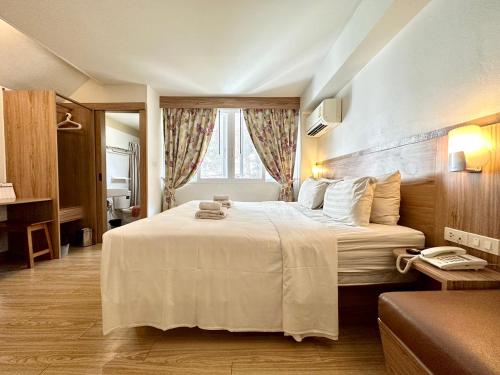 a bedroom with a large white bed with a window at Dinsomon Hotel in Bangkok