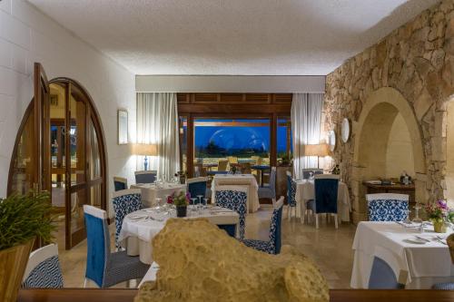 a restaurant with tables and chairs and a stone wall at Hotel Ta' Cenc & Spa in Sannat