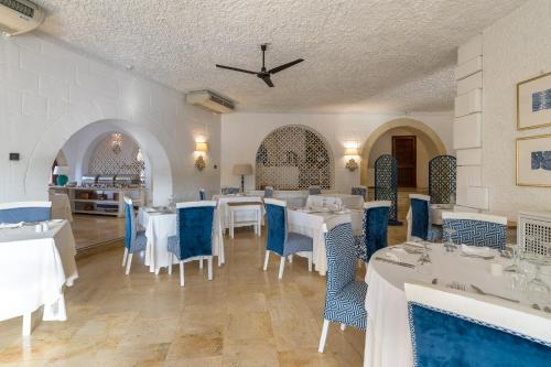 a dining room with white tables and blue chairs at Hotel Ta' Cenc & Spa in Sannat