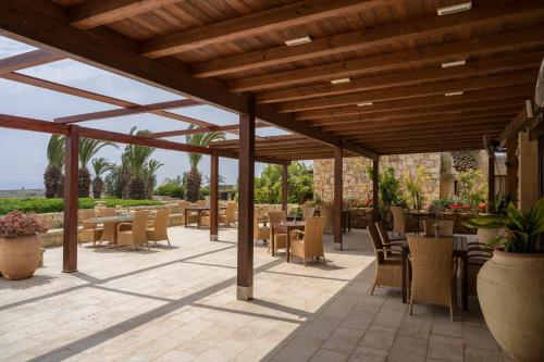 a patio with tables and chairs under a wooden pergola at Hotel Ta' Cenc & Spa in Sannat
