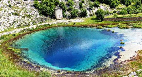 a large blue pool of water in a field at Apartman Stela in Knin