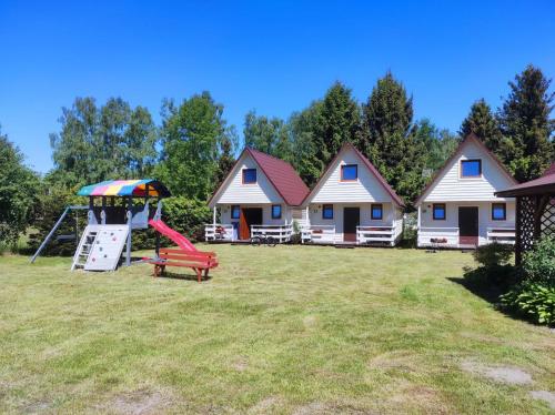a yard with houses and a playground with a swing at Domki Letniskowe Bryza in Jarosławiec